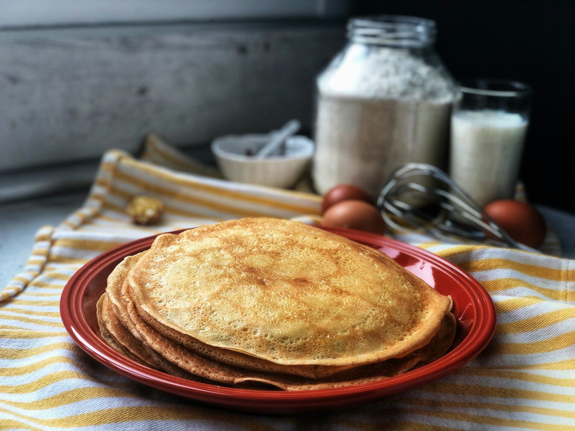 Stack of thin Swedish pancakes with lingonberry jam and whipped cream